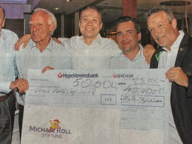 Fünf Männer präsentieren bei Charity-Gala einen Riesenscheck; Spendenübergabe mit HypoVereinsbank/UniCredit-Logo