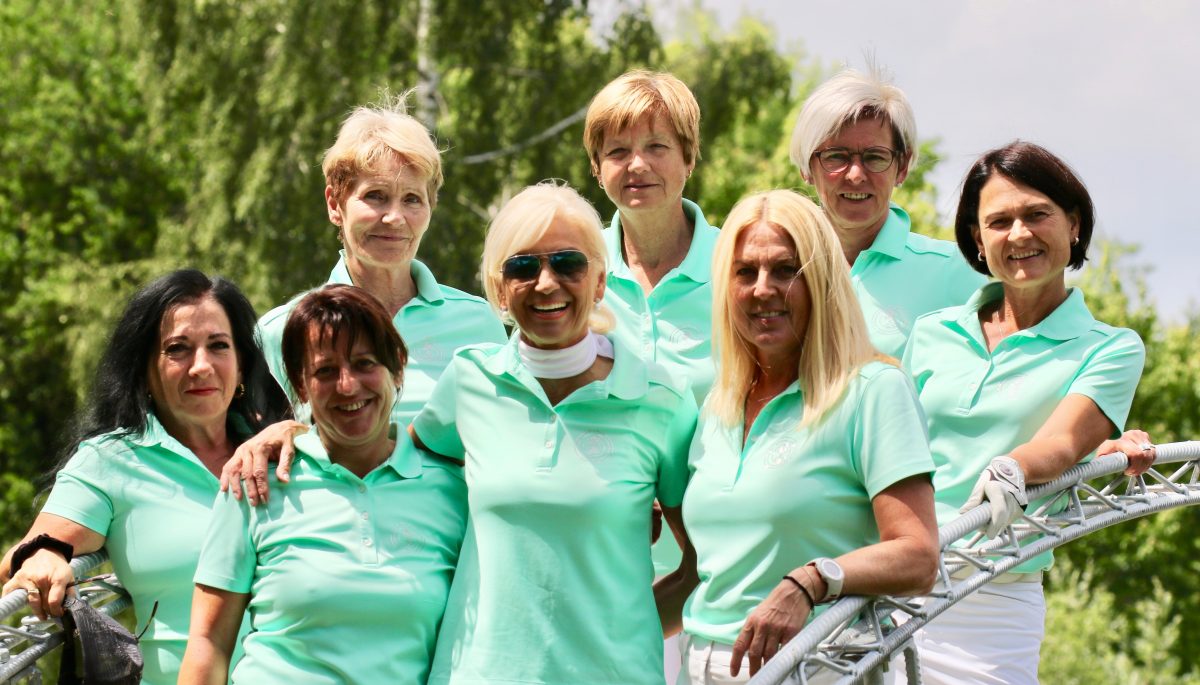 Damen-Golfteam Gruppenfoto: Frauen in mintgrünen Poloshirts lachen auf dem Golfplatz im Sommer
