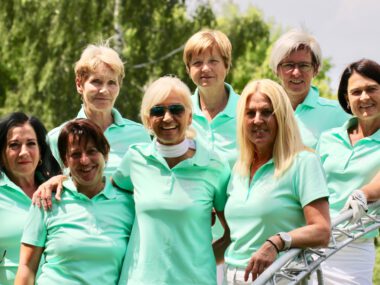 Damen-Golfteam Gruppenfoto: Frauen in mintgrünen Poloshirts lachen auf dem Golfplatz im Sommer