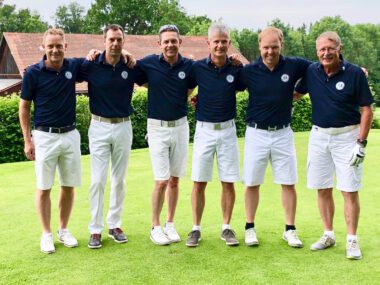 Sechs Golfer als Golfteam posieren auf dem Grün – Mannschaftsfoto im Golfclub, blaue Poloshirts, weiße Shorts