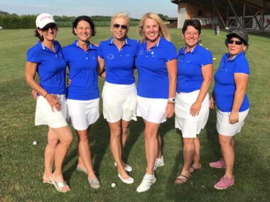 Golfteam Damen in blauen Polos und weißen Röcken auf der Driving Range, Mannschaftsfoto bei Sonnenschein